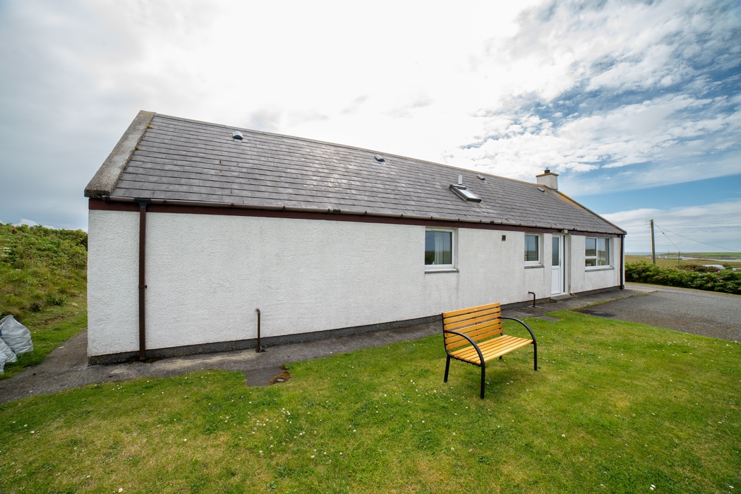 Am Bliochan self catering cottage north uist - exterior view with bench.
