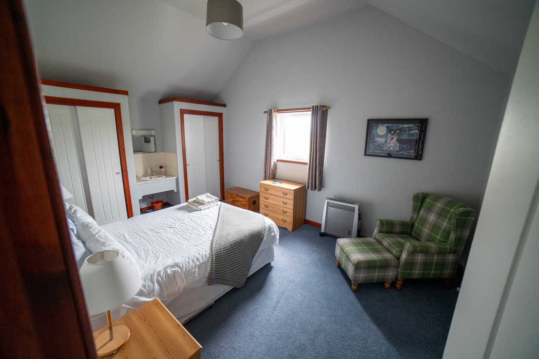 Am Bliochan self catering cottage north uist - double bedroom with chair and footstool.